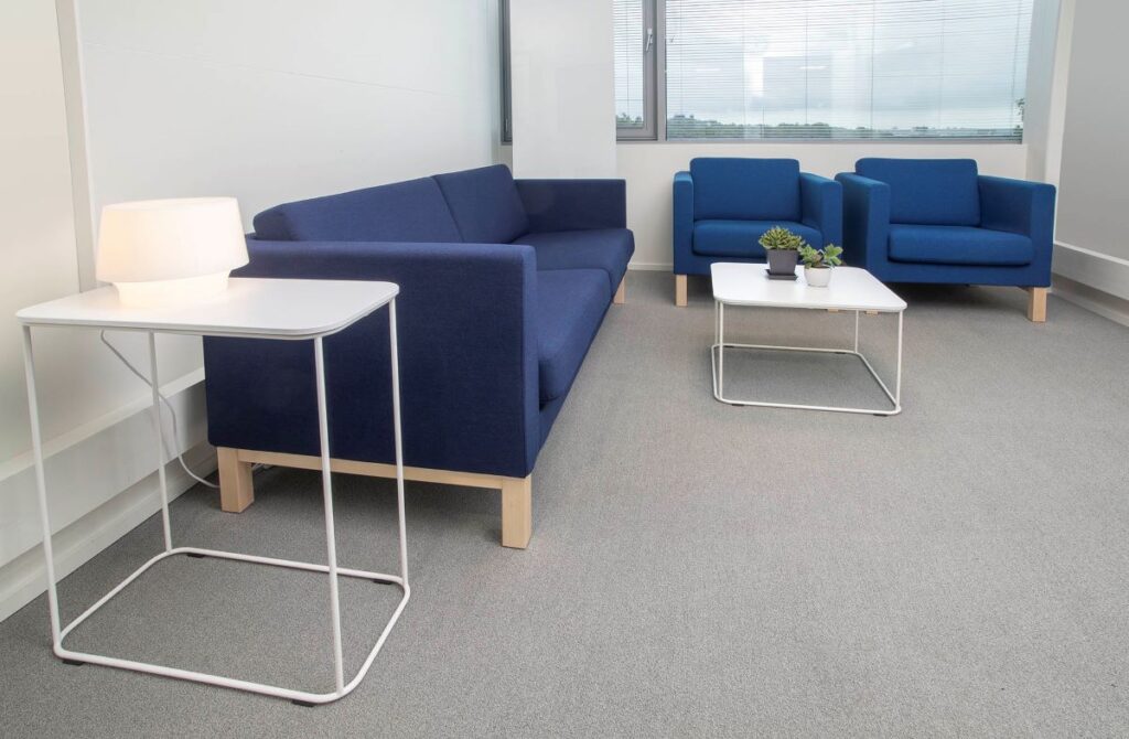 Ikkunallinen huone, jossa on sohva ja kaksi nojatuolia sekä pienet pöydät.