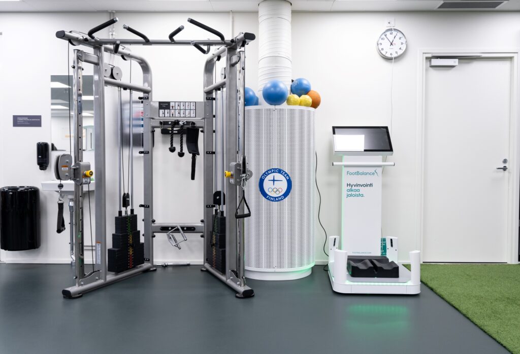 Korkea taljalaite, jonka vieressä Footbalance-laite. Seinällä Olympic Team Finland -kyltti